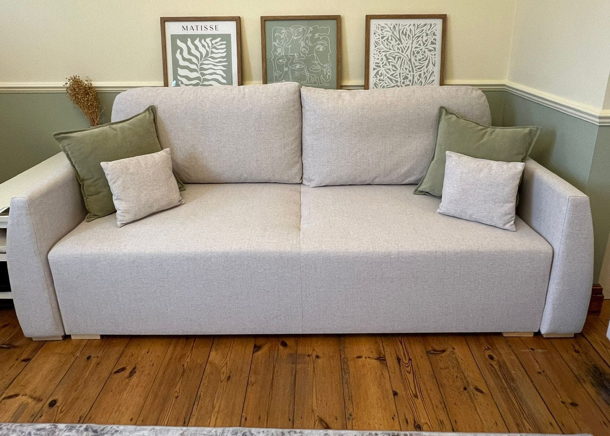 Gray sofa with decorative pillows in a room with framed pictures on the wall.